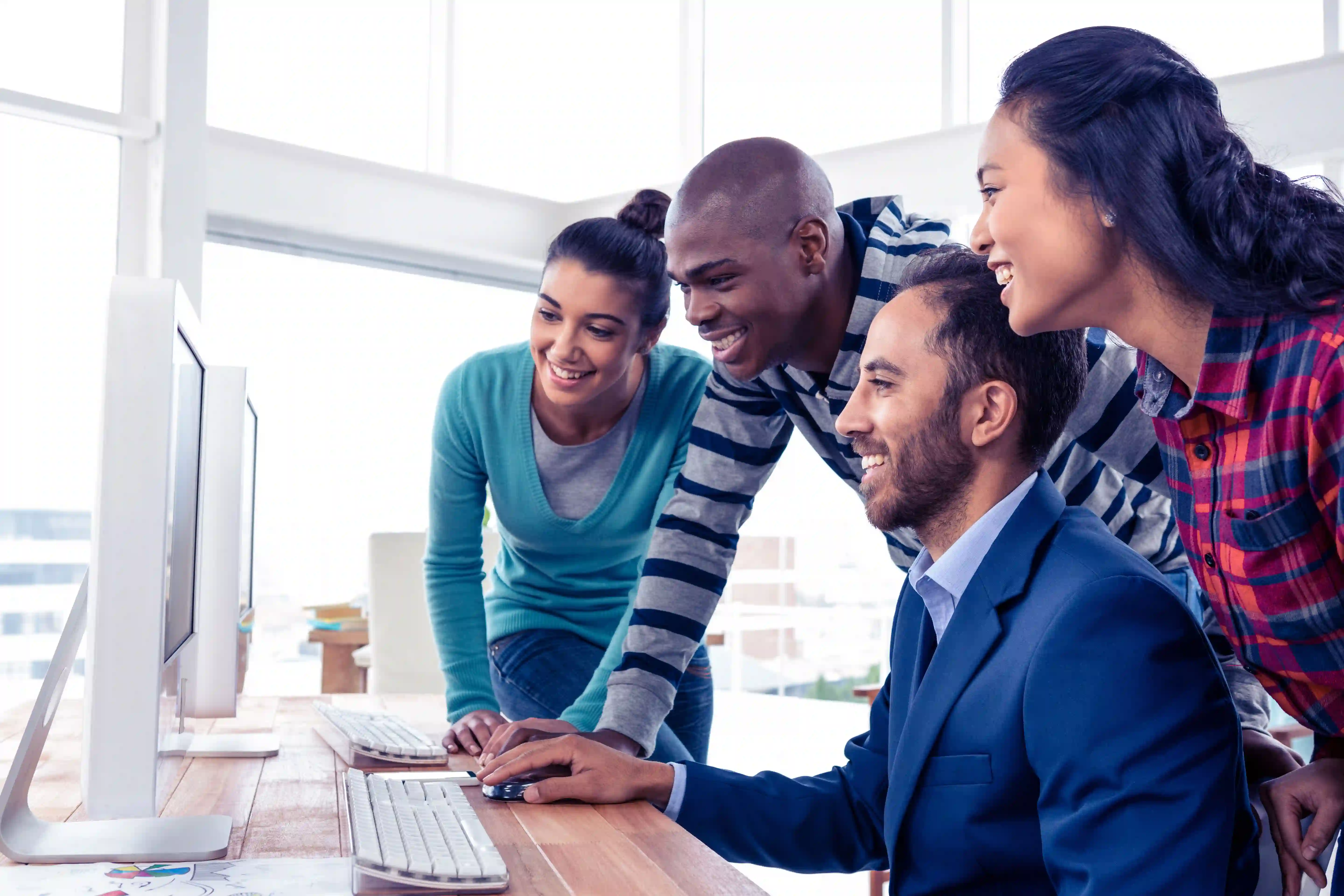 Happy coworkers look at a monitor.